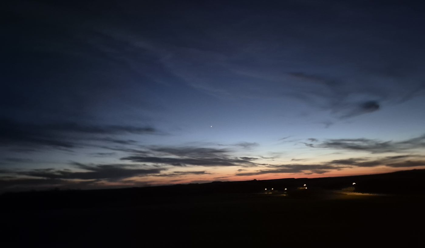 Evening light over dark fields and distant lights around Muirkirk.